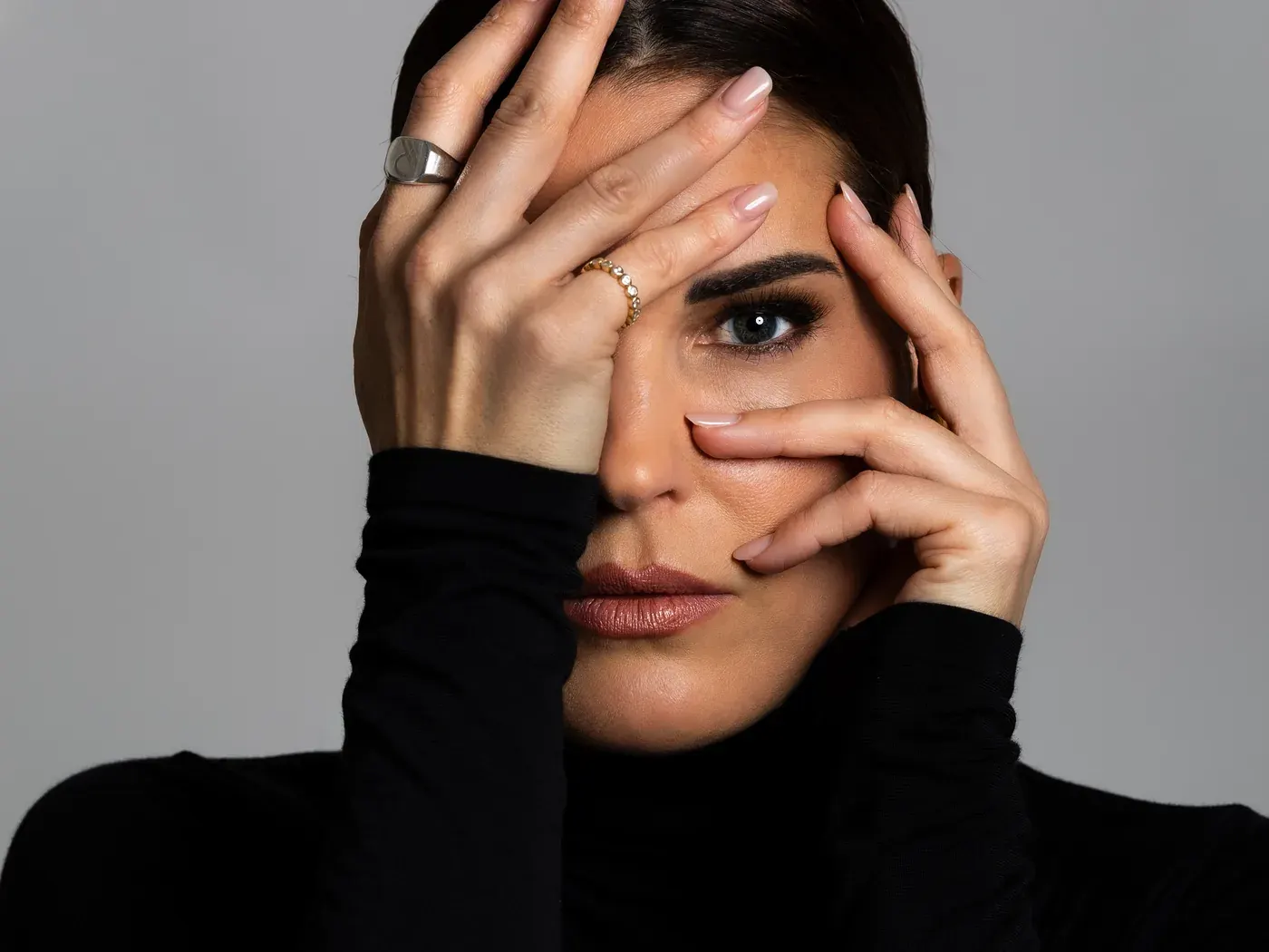 Elke Rock hält eine Hand vor das Gesicht und blickt durch die Finger